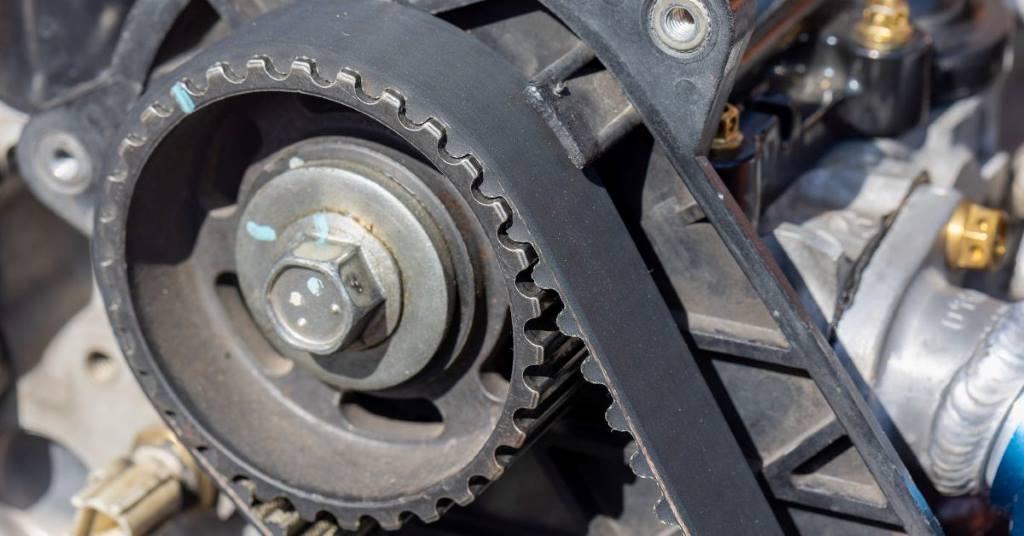 Worn vs new timing belt comparison showing cracks and wear on Mazda MPV part